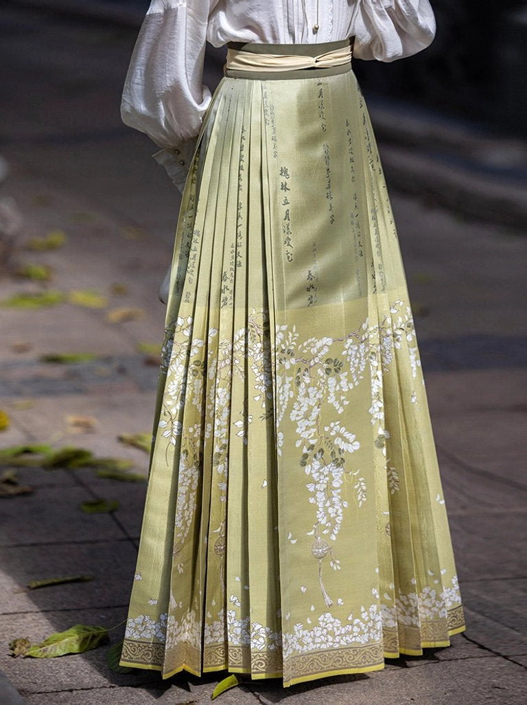 Sage green pleated mamianqun skirt with white acacia flower and traditional calligraphy print, floral hem trim, and matching waist sashes