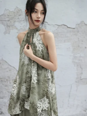 Close-up view of a sage green Chinese-style Hanfu halter top with keyhole neckline, draped silhouette, and delicate white chrysanthemum embroidery