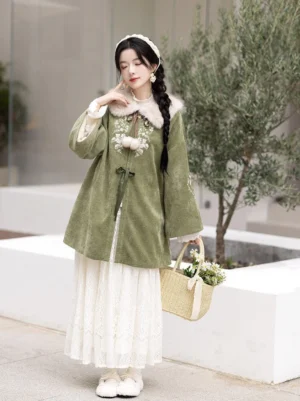 Sage green modern Hanfu jacket with faux fur collar, floral embroidery, wide bell sleeves, drawstring waist, and white lace skirt styling