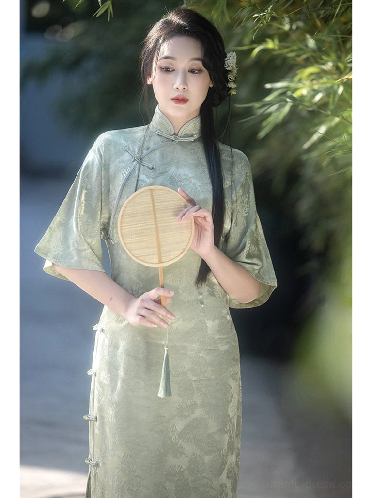 Close-up view of sage green modern Hanfu qipao dress featuring floral jacquard fabric, Mandarin collar, traditional frog buttons, and tassel round fan