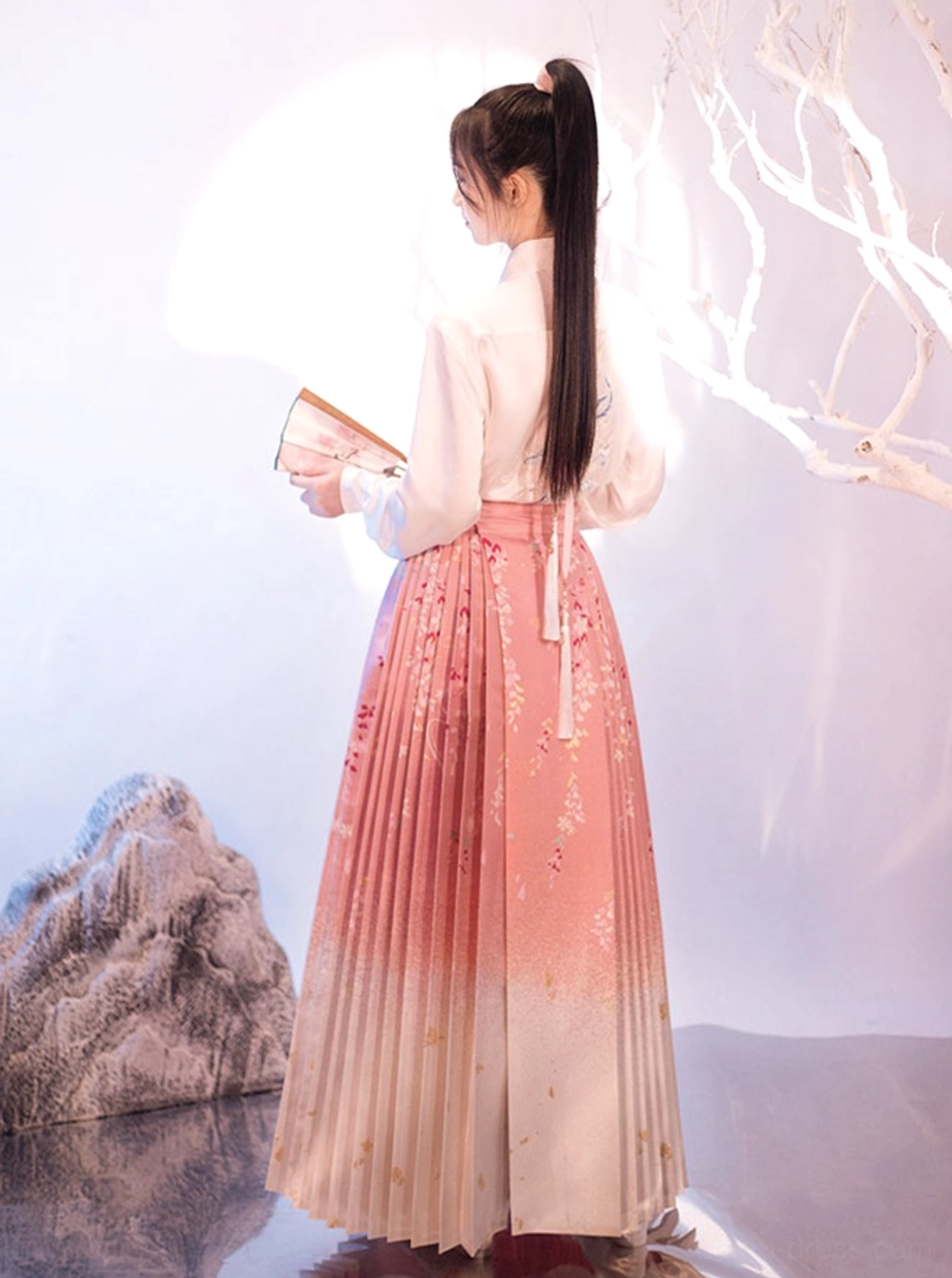 Rear three-quarter view of pink and ivory Sakura Mamianqun horse face skirt showing pleated back silhouette and waist strap detail