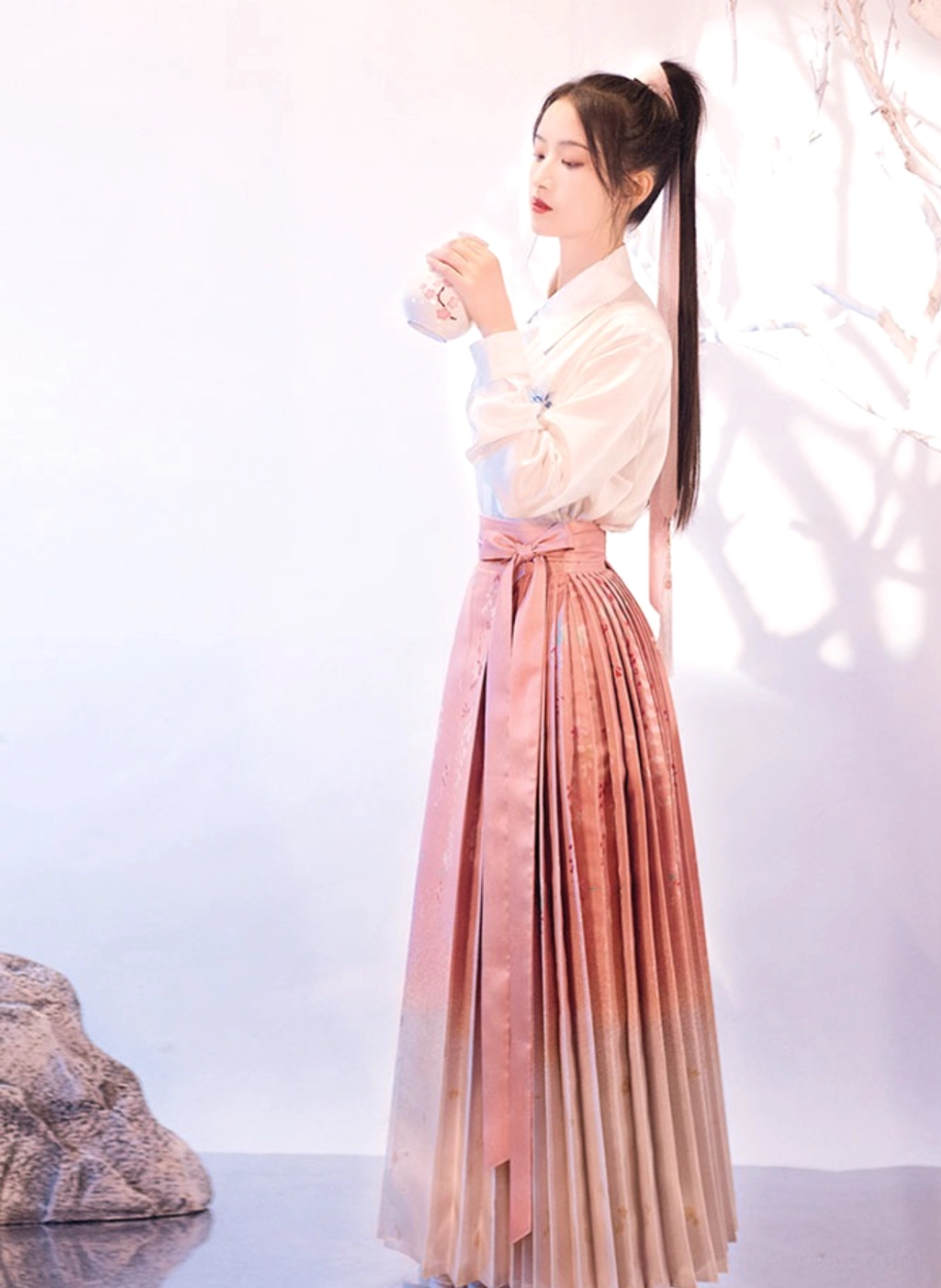 Side profile of modern Ming style Sakura Mamianqun horse face skirt with pink satin ombre pleats and delicate floral print