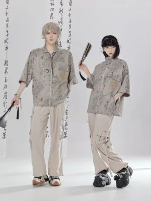 Modern Hanfu Chinese style zipper shirt and wide-leg cargo pants outfit in sand khaki with traditional ink-inspired prints, shown on two models against a Chinese calligraphy studio backdrop