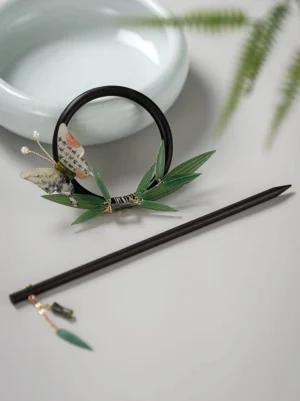 Traditional Chinese bamboo butterfly back hair pin flat lay with dark wood hair stick, circular fastener, green leaves and pearl butterfly detail