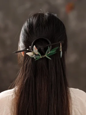 Sandalwood bamboo butterfly Hanfu back hair pin worn in long straight hair, showing dark circular hair fastener and jade-style tassel from the back