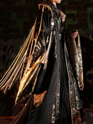 Back three quarter view of the Star Priest male hanfu costume showing shimmering black satin fabric, gold embroidered robe hem, wide sleeves, shoulder ornament, and cascading ceremonial tassels