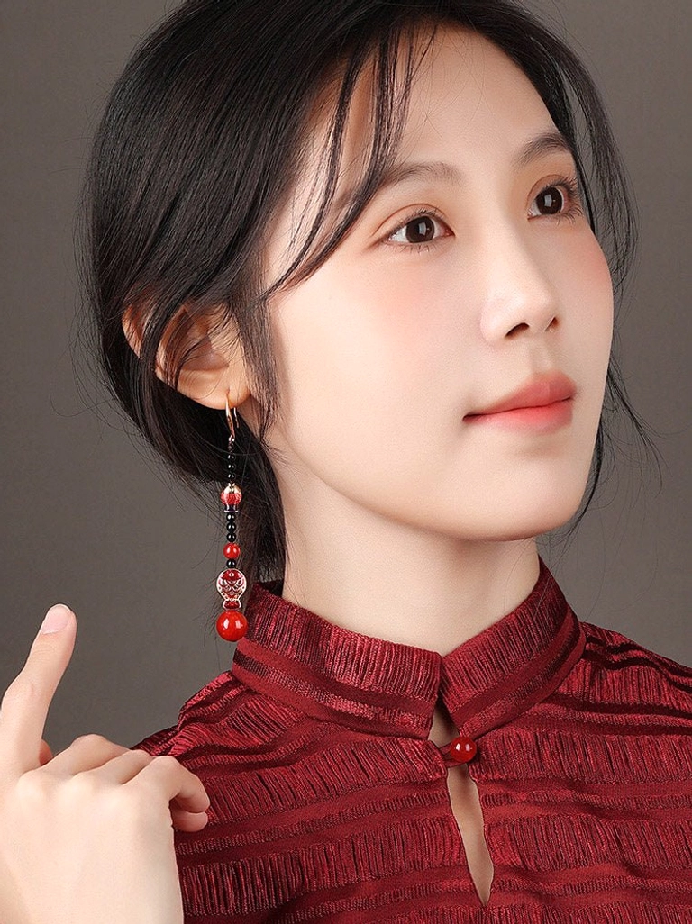 Three-quarter portrait of a model highlighting scarlet koi fish Chinese earrings while wearing a traditional red cheongsam