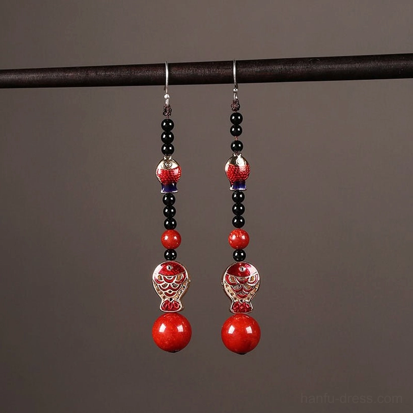 Complete pair of scarlet koi fish drop earrings displayed on a black hanger with dangling chains and red bead pendants