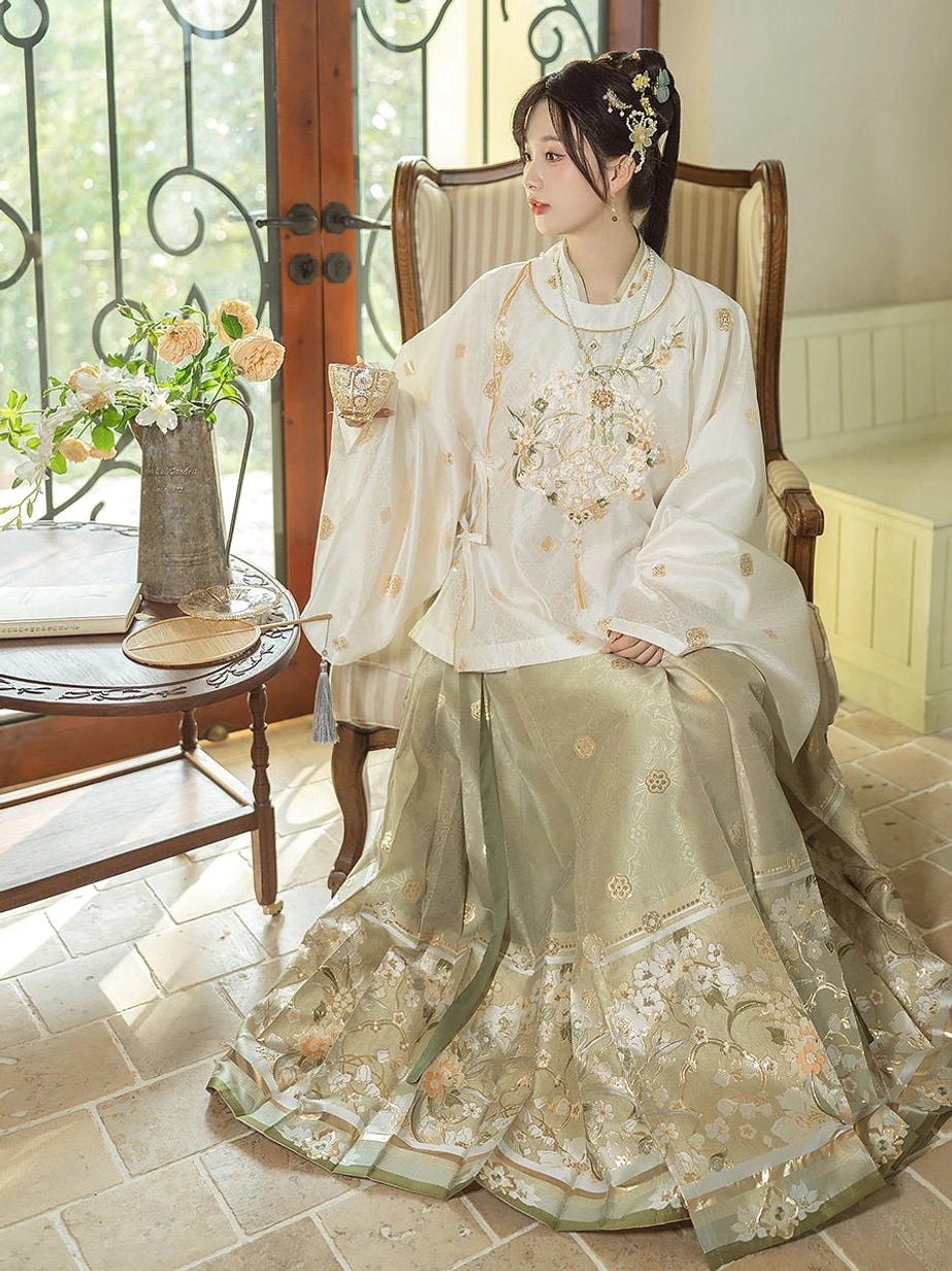 Woman seated in a Ming Dynasty Hanfu outfit featuring chest embroidery tassel detail and layered decorated Mamian skirt hem