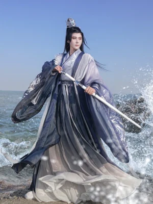 Front full-body view of Shadowborne Blade Cheng Ying Jian wuxia hanfu for men with blue gradient layered robes, phoenix embroidery, flowing sleeves, and ceremonial sword beside the sea