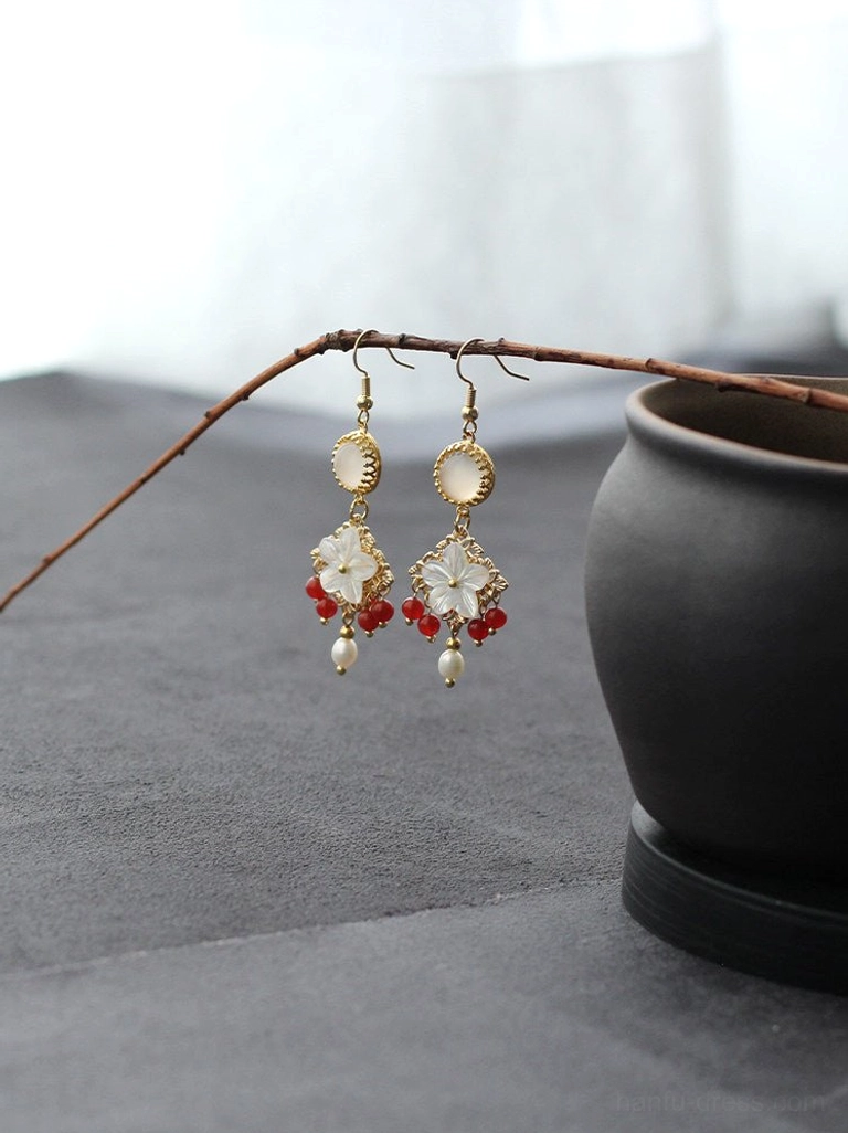 Pair of Chinese shell flower drop earrings with pearl tassels and red beads hanging from a natural dry branch
