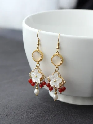 Side view of Chinese inspired shell flower dangle earrings with red agate style beads and freshwater pearl pendants