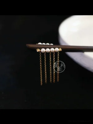 Shooting Stars pearl tassel Chinese hair stick with dark brown pin and gold tone chains displayed on white embossed porcelain