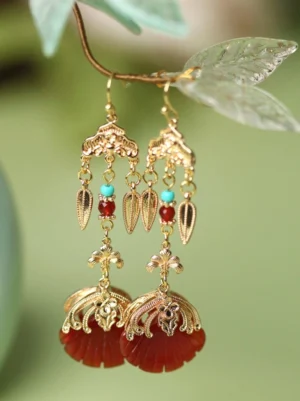 Gold filigree Chinese Hanfu drop earrings hanging on green leaves with red fan pendants, turquoise blue beads, and delicate tassel details