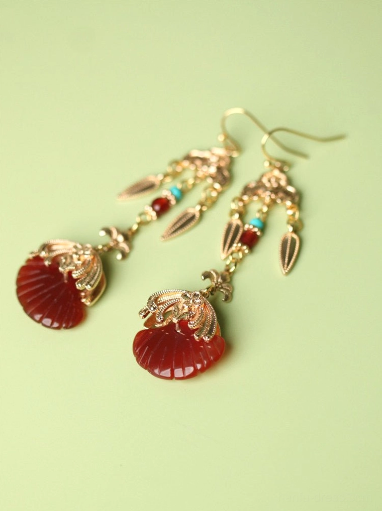 Flat lay of hook closure Chinese Hanfu earrings with gold-toned filigree details, red fan-shaped drops, and turquoise bead accents