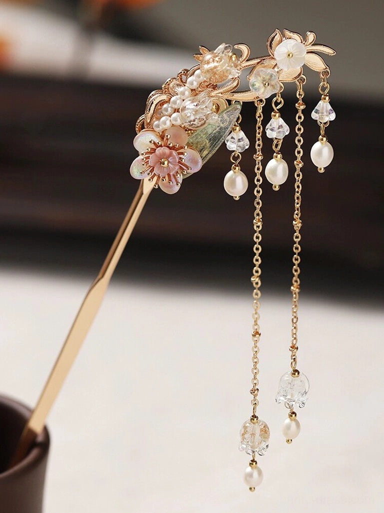Side view of a champagne gold Chinese hair stick decorated with pink flowers, glazed leaves, imitation pearls, crystal pendants, and tassels