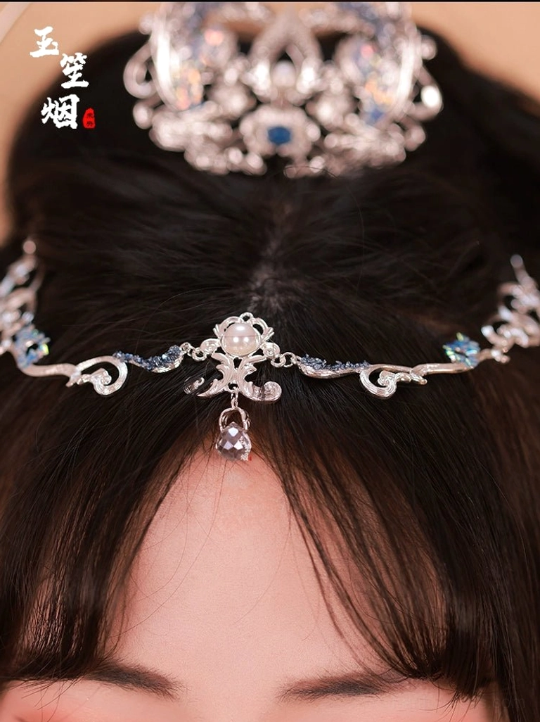 Close-up of silver blue Hanfu forehead chain and crown with crystal accents faux pearl pendant and intricate traditional Chinese scrollwork