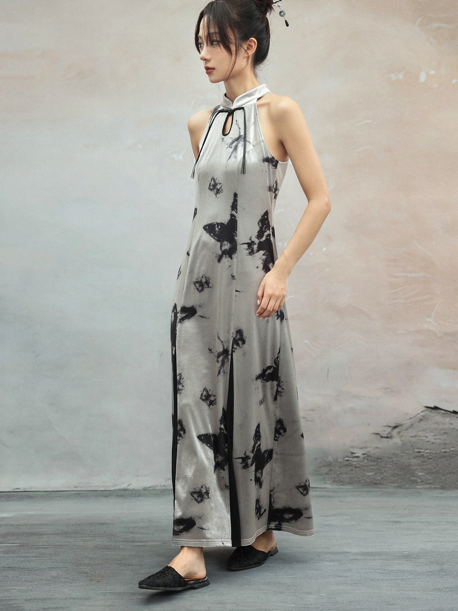 Side profile of a fitted silver butterfly print cheongsam dress highlighting the elegant long silhouette, high side slit, and artistic black ink-wash pattern