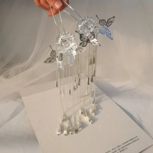 Close-up of a silver butterfly tassel hair pin held by hand, featuring openwork butterfly ornaments, floral detail, and long dangling chains for Hanfu hairstyles