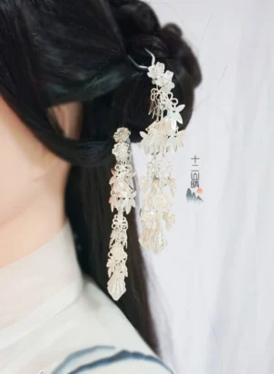 Close-up side view of silver Chinese hairpins with delicate filigree flowers and layered tassel decorations in a half-up Hanfu hairstyle