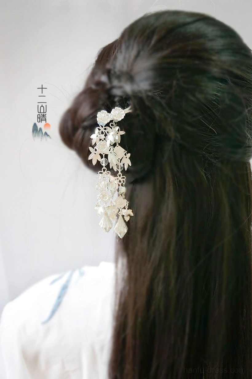 Rear view of a silver Chinese Hanfu hairpin with clustered flowers and leaf-shaped tassel pendants worn in a loose half-up hairstyle