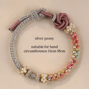 Silver peony handwoven Chinese knot bracelet with grey braided cord, dusty rose floral knot charm, colorful bead accents, and adjustable loop closure on a light beige background