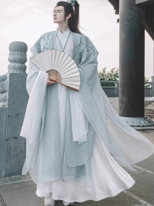Full length side view of men's Silver Scale xianxia hanfu set with cyan outer coat white layered skirt and folding fan