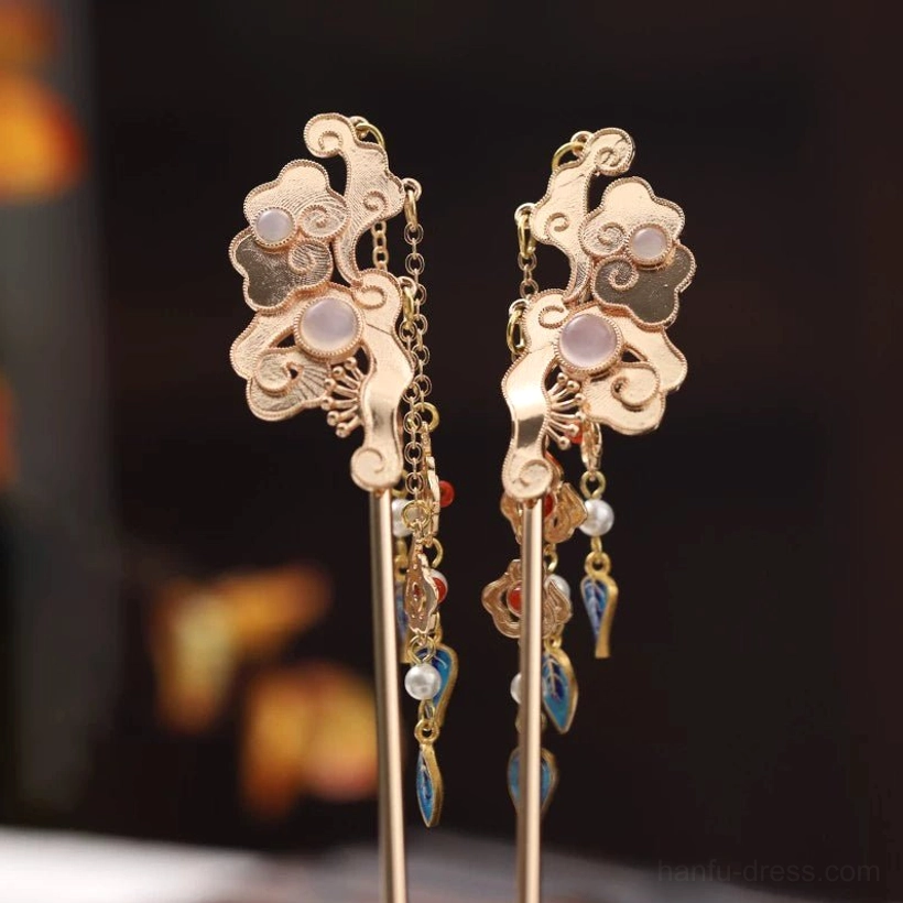 Pair of simplified Chinese cloud hair sticks with gold-tone metal, round pink inlays, short tassels, red beads, pearl details, and blue decorative charms