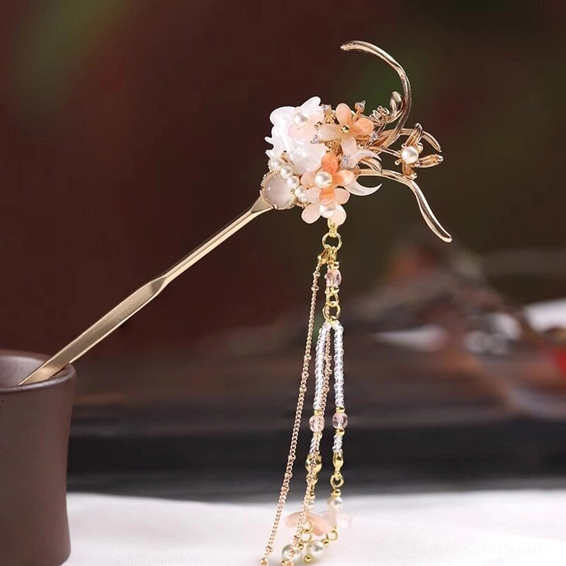Single gold-toned Chinese hair stick with pink and white floral clusters, pearl details, two cascading tassel chains, and a flower pendant
