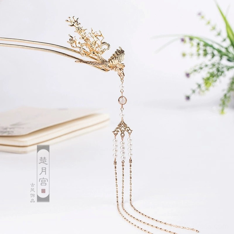 Single golden phoenix hairpin shown from a three-quarter angle with intricate foliage carving layered tassels and a round decorative bead