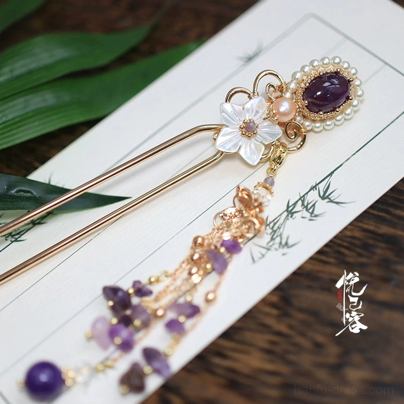 Single traditional Chinese hair pin with long gold chain tassel purple amethyst beads and round purple pendant arranged on vintage bamboo-patterned paper