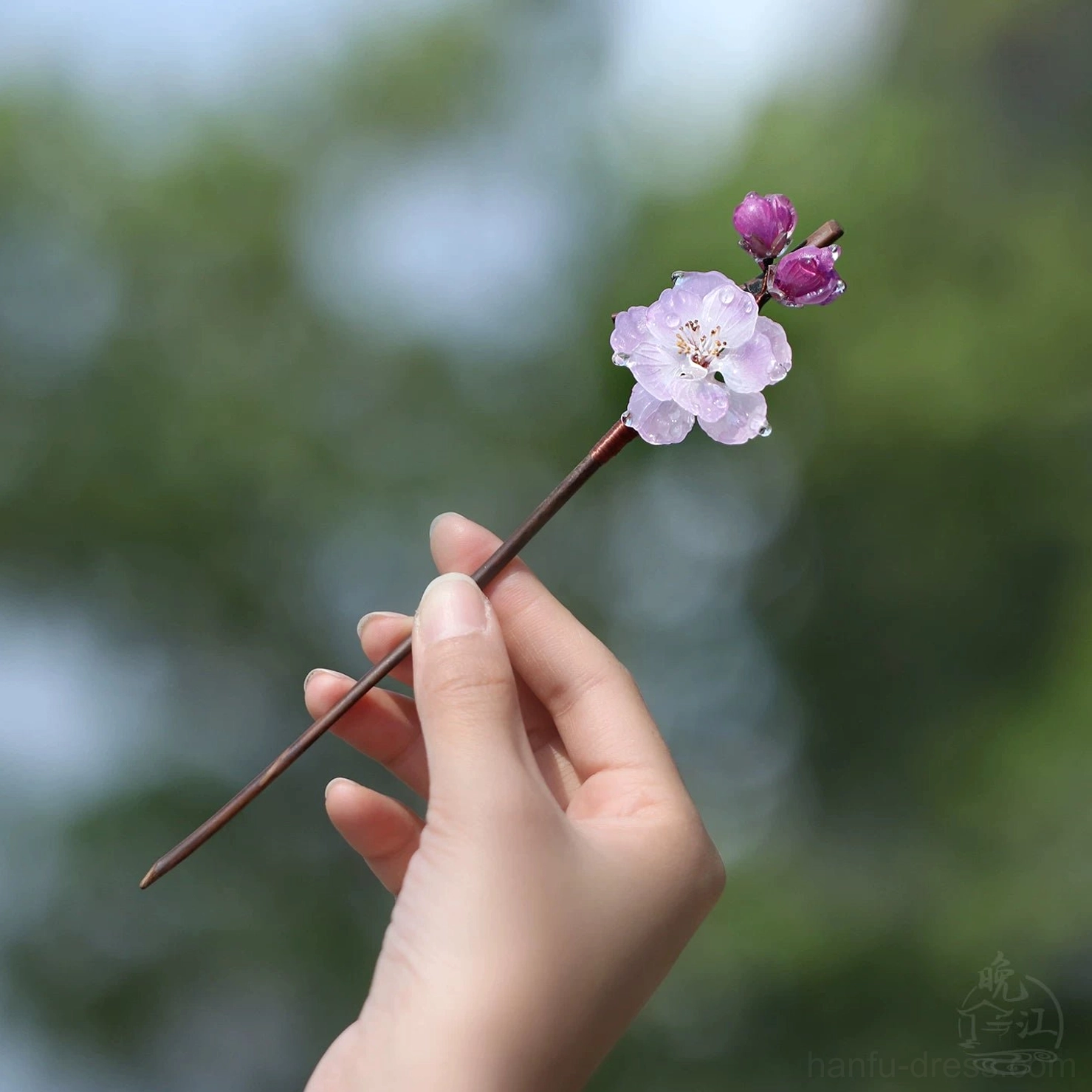 Side close-up of a single-stem Chinese hair stick featuring a compact cluster of pink plum blossoms and purple flower buds