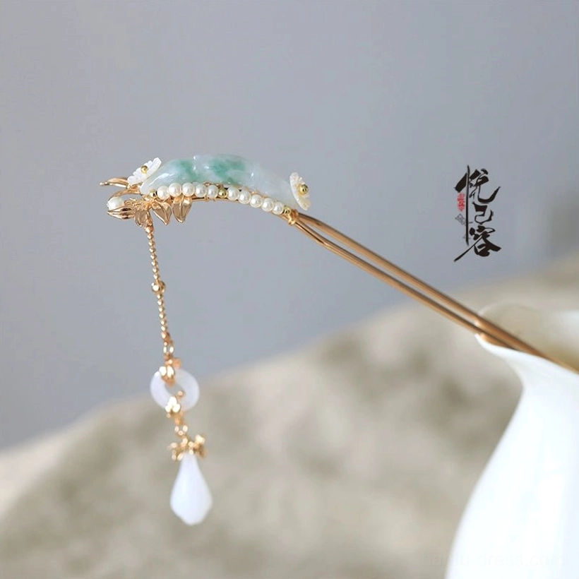 Single Yulan traditional Chinese jade tassel hair pin with gold-toned metal white flower accents and teardrop pendant beside a ceramic vase