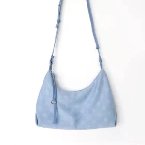 Sky blue crescent shoulder bag with embossed floral pattern, adjustable strap, and decorative leather tassel displayed against a white background