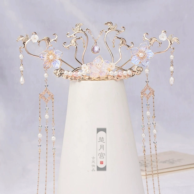 Sky Phoenix hanfu hair crown with gold toned metal vines, iridescent blue purple glass flowers, pearl drops, and long flowing tassels displayed on a white ceramic vase