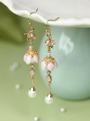 Sleeping flower Chinese earrings with pink bell blossom pendants, gold floral hooks and pearl drop charms displayed on a celadon tray