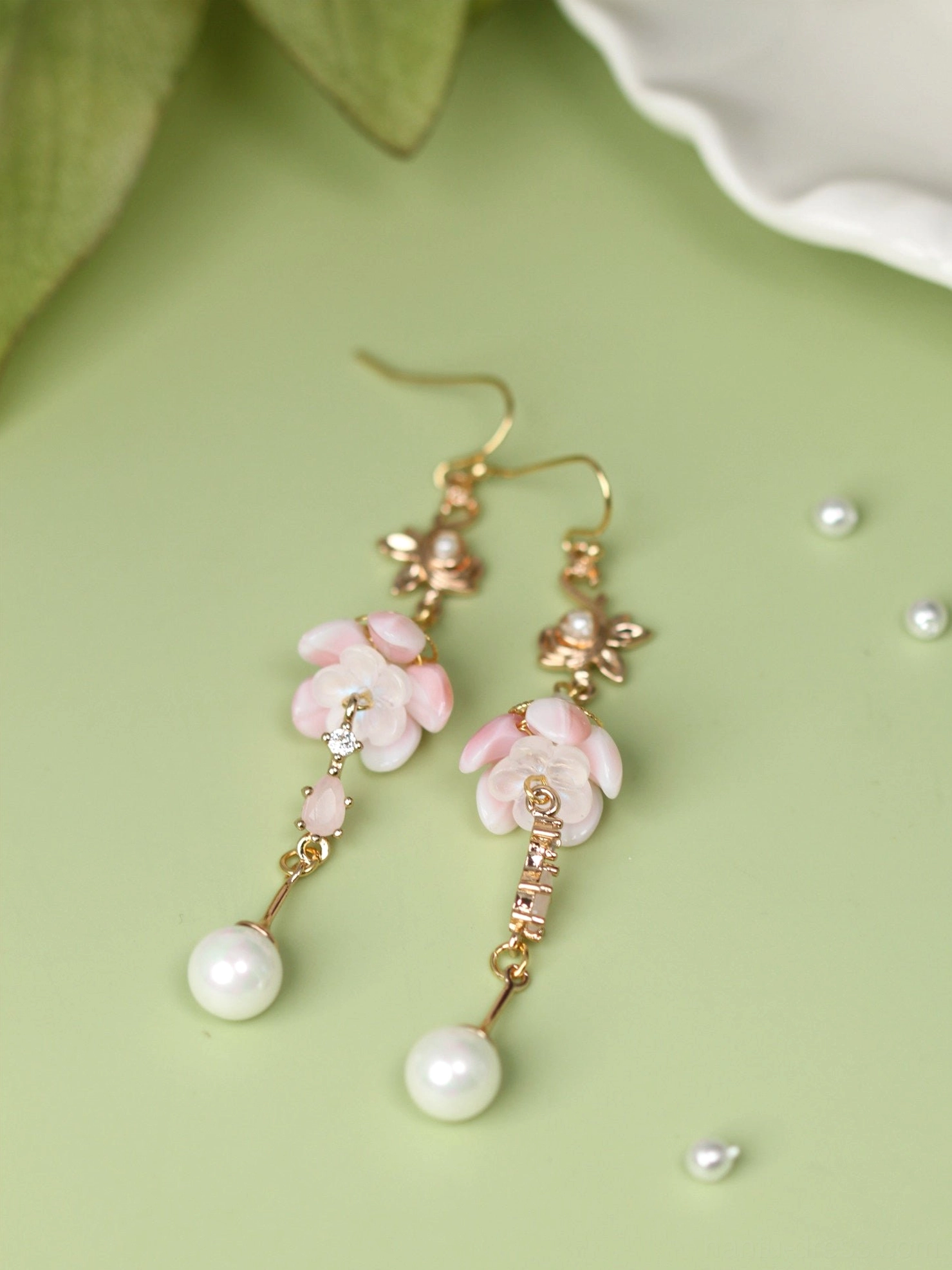 Flat lay view of sleeping flower Hanfu earrings showing open pink petal pendants, textured gold chain details and pearl drops