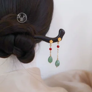 Sleepless Flower ebony Chinese hair stick worn in a traditional coiled bun with gold flower ornament red bead tassels and green jade drop pendants
