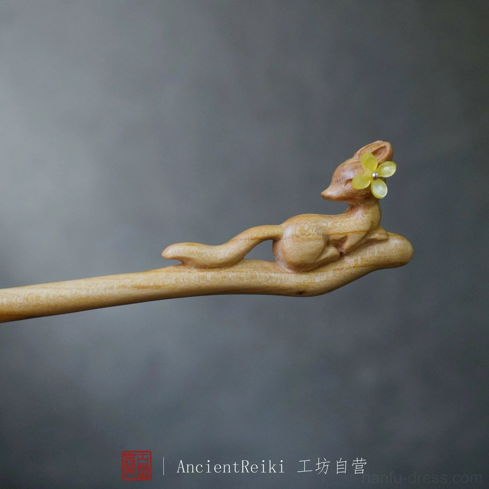 Side close-up of a smooth carved wooden fox Chinese hairpin with natural wood texture and yellow flower ornament