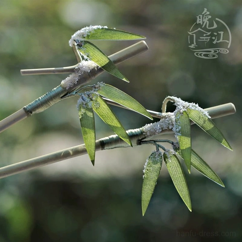 Snow bamboo Chinese hair stick with lifelike green bamboo leaves simulated snow details and wrapped cord decoration displayed against a natural green background