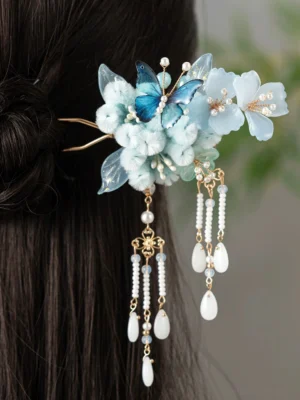 Traditional Chinese blue butterfly flower tassel hair stick worn in long dark hair, showing the golden double-pronged fork and layered Hanfu hair accessory details