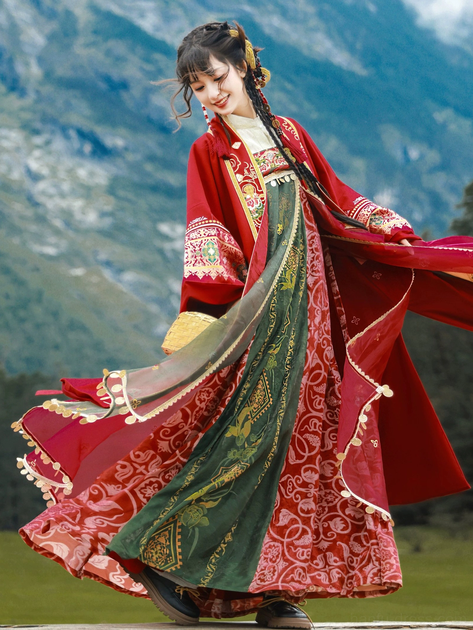 Modern Dunhuang Tang Dynasty Hanfu festive outfit with red embroidered coat and flowing red green wrap dress photographed on an alpine grassland