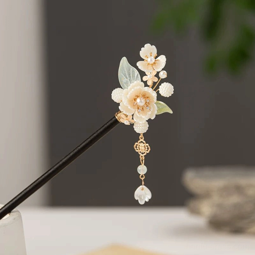 Right-side close-up of a traditional Chinese floral hair stick featuring snow hibiscus blossoms, pearl-style flower centers, light green leaves, gold-tone details, and a delicate simplified tassel