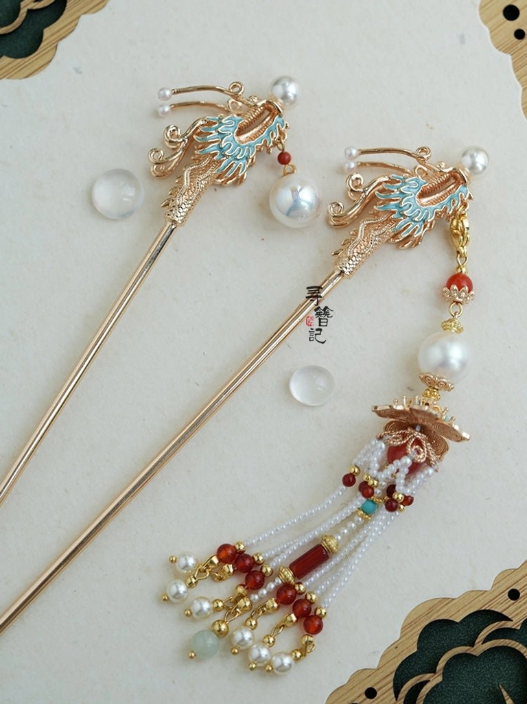 Top view of a Soaring Dragon Chinese Hanfu hairpin with a blue enamel dragon motif, gold-tone metal frame, white pearl beads, red agate-style accents, turquoise beads, and a long layered tassel
