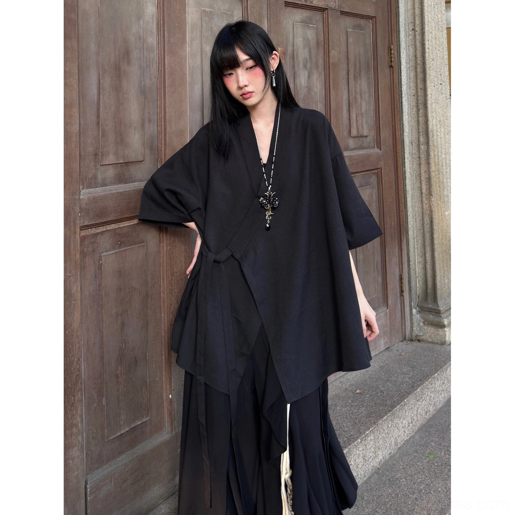 Three-quarter view of a solid black modern Hanfu cross-collar cardigan with minimal draped design and loose half sleeves