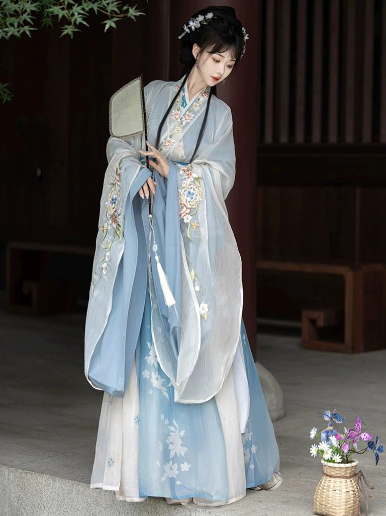 Solid light blue Wei Jin Dynasty Qiyao Ruqun Hanfu half-body view with white floral prints, embroidered wide sleeves, cross-collar neckline, and folding fan