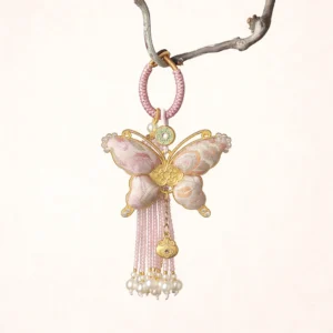 Pastel pink Song brocade butterfly Chinese keychain and handbag charm with braided loop, pearl-like bead tassel, gold-toned ornaments, and decorative pendants hanging from a tree branch