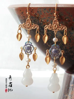 Song Dynasty inspired Chinese lantern drop earrings with gold filigree longevity motif pearls leaf charms and white gourd drops displayed beside a ceramic bowl