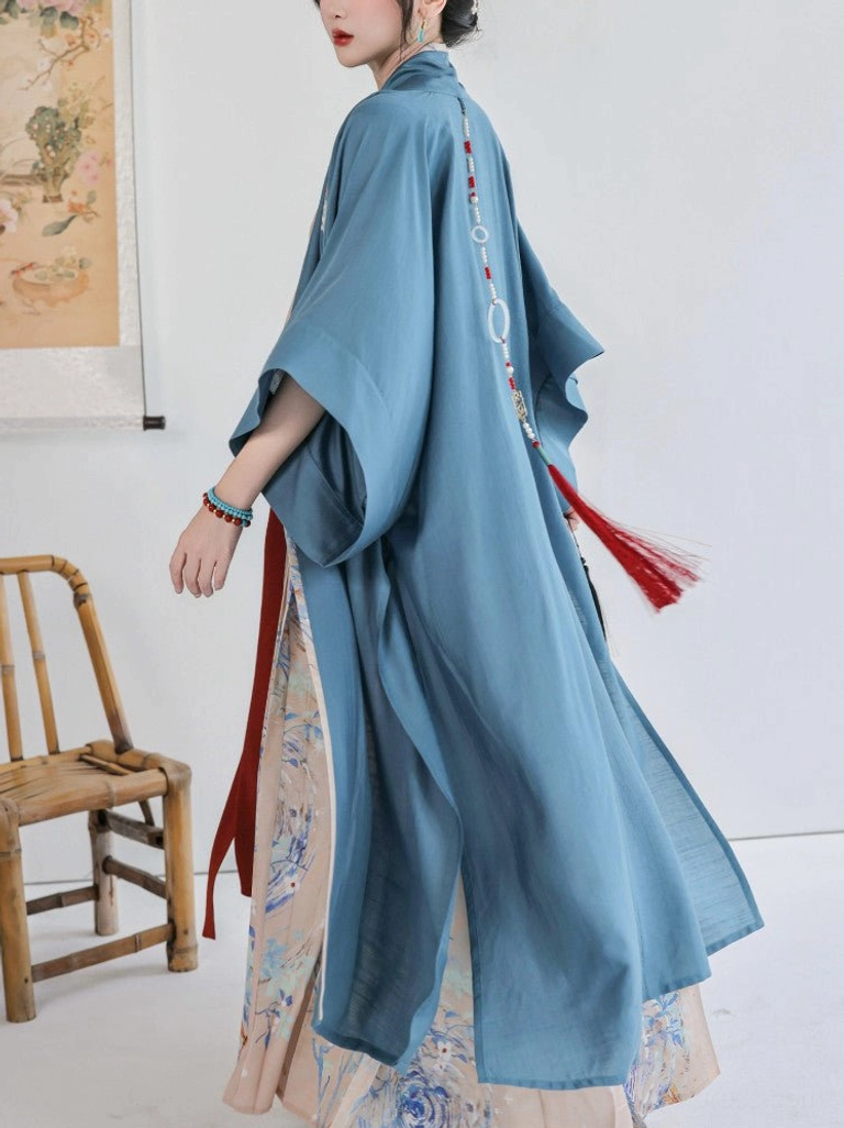 Back view of a modern Song Dynasty Hanfu set with long dusty blue Beizi jacket, flowing hem, decorative red tassel pendant, and traditional Chinese studio styling