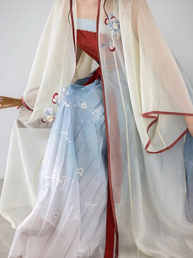 Close up detail of Song Dynasty Hanfu cardigan embroidery, red trim, and blue white gradient floral pleated skirt